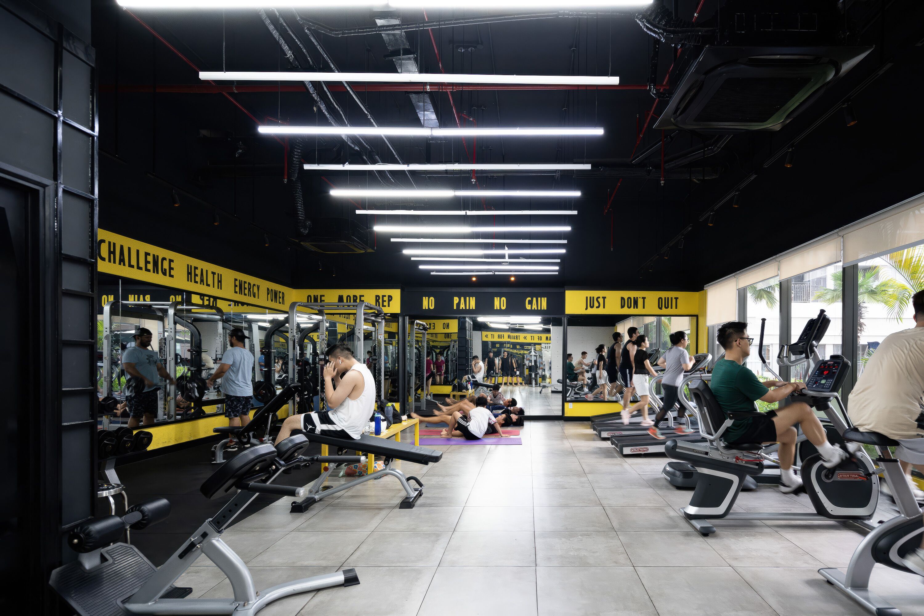 Un gimnasio con diversos equipos de ejercicio, espejos y letreros motivacionales.