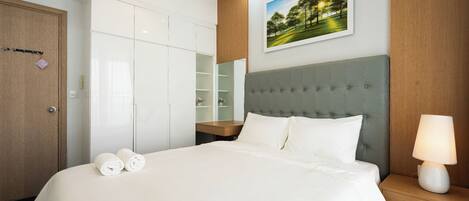 Una habitación de hotel con una cama grande, una mesita de noche con lámpara, un armario, un espejo y un cuadro en la pared.