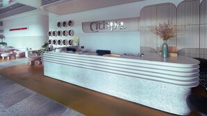 Un moderno mostrador de recepción con un diseño circular único, un letrero montado en la pared y un jarrón decorativo.