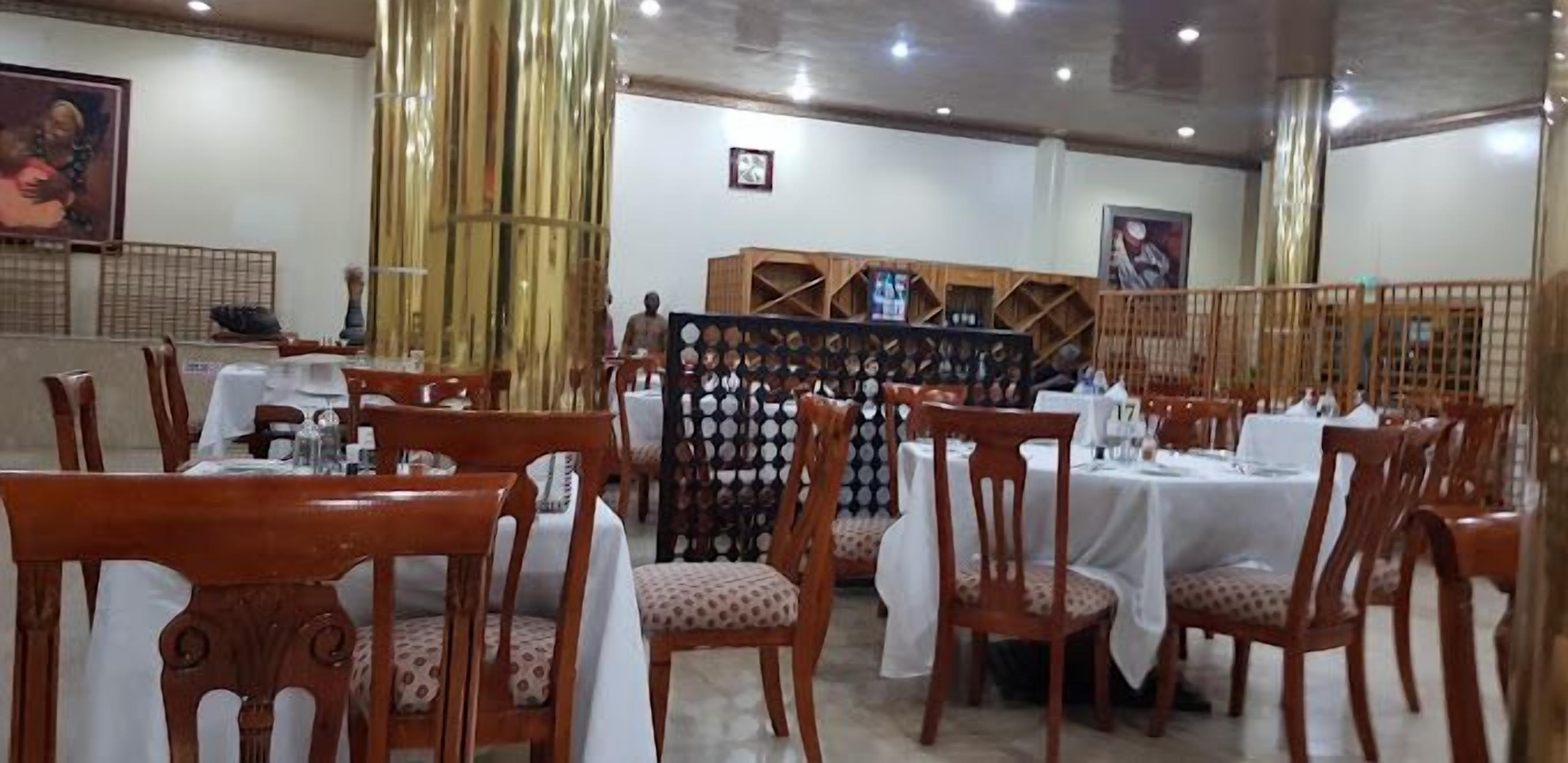 Ein Restaurant mit Holztischen und -stühlen, einer Wand mit gerahmten Bildern und einem Wandbild im Hintergrund.