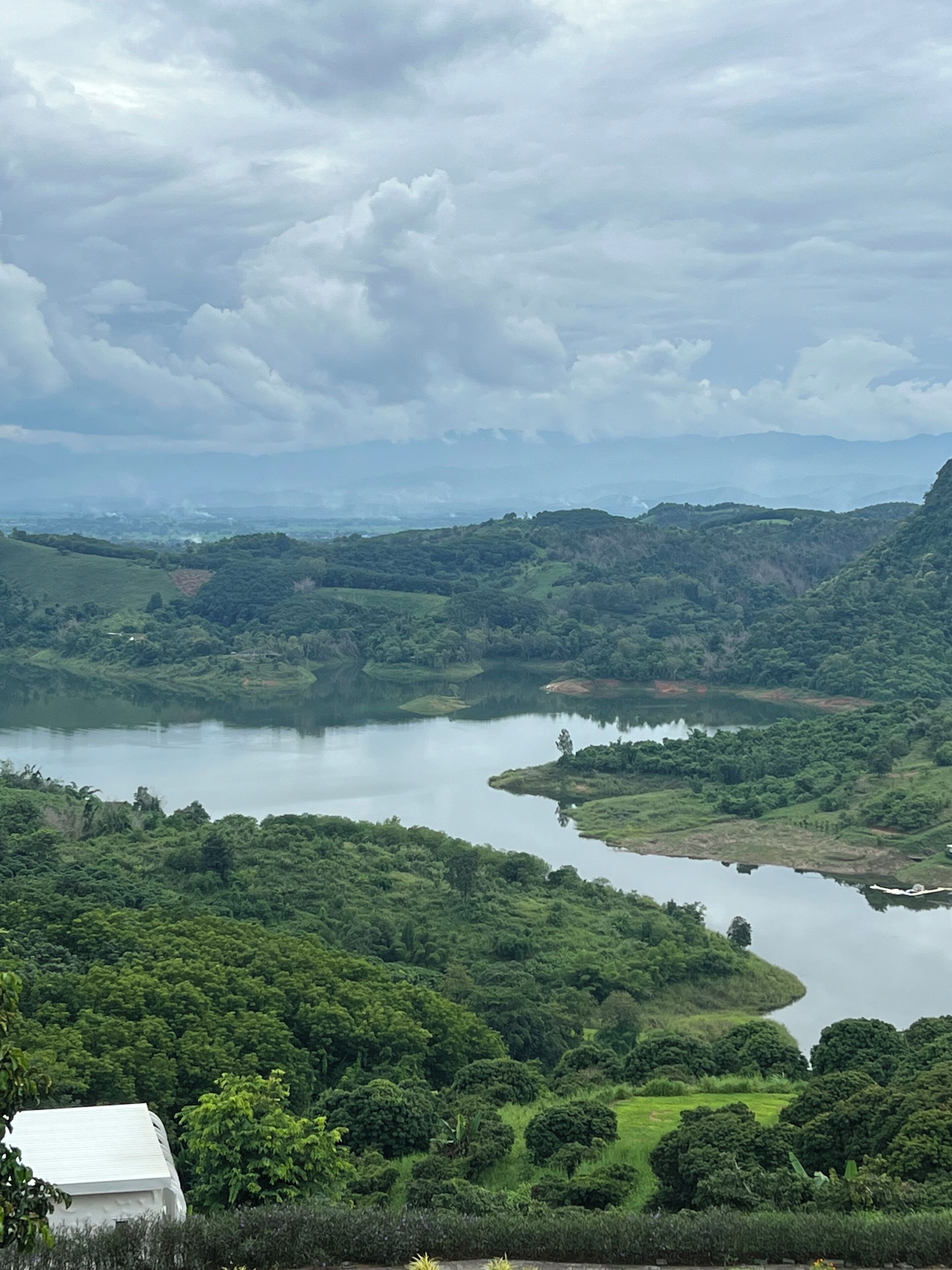 A panoramic view of a lush green landscape with a river meandering through it, surrounded by hills and dense vegetation.