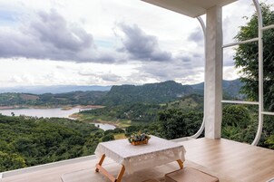 Une pièce avec une table et des chaises, une vue sur un lac et des montagnes, et une grande fenêtre.