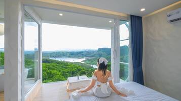 A room with a large window offering a view of a lush landscape.