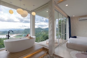 Une salle de bain moderne avec une baignoire sur pieds, de grandes fenêtres et une vue sur une rivière et des montagnes.