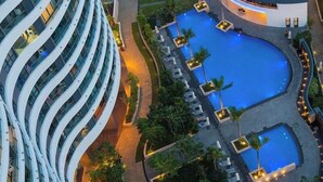 A modern hotel with a curved building, a central swimming pool, and surrounding greenery. - City Garden Suites - Panorama Penthouse (Ho Chi Minh City)