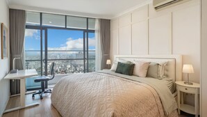 A modern hotel room with a large bed, a desk, and a view of the city. - City Garden Suites - Panorama Penthouse (Ho Chi Minh City)