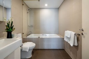 Moderni kylpyhuone, jossa on kylpyamme, wc ja pesuallas.