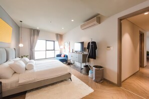 Moderni hotellihuone, jossa on suuri sänky, työpöytä, televisio ja vaatekaappi.