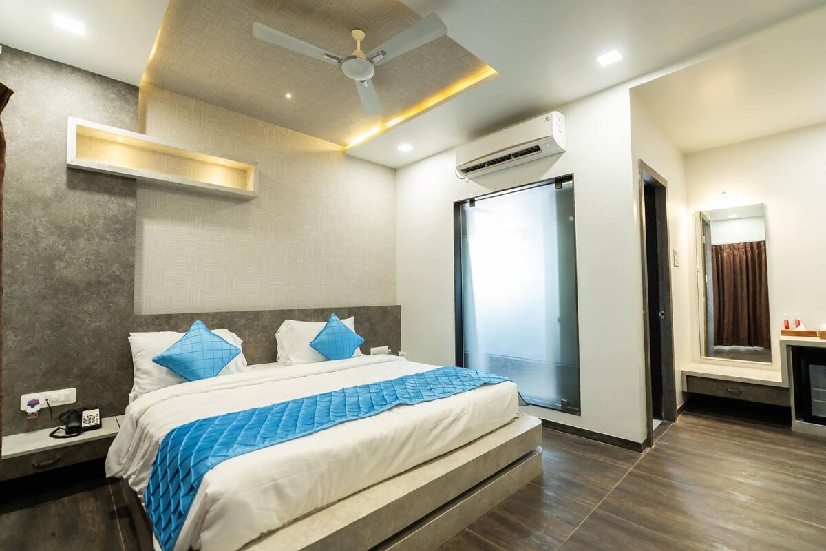 Een moderne hotelkamer met een groot bed, een plafondventilator, een airconditioning en uitzicht buiten via een glazen deur.