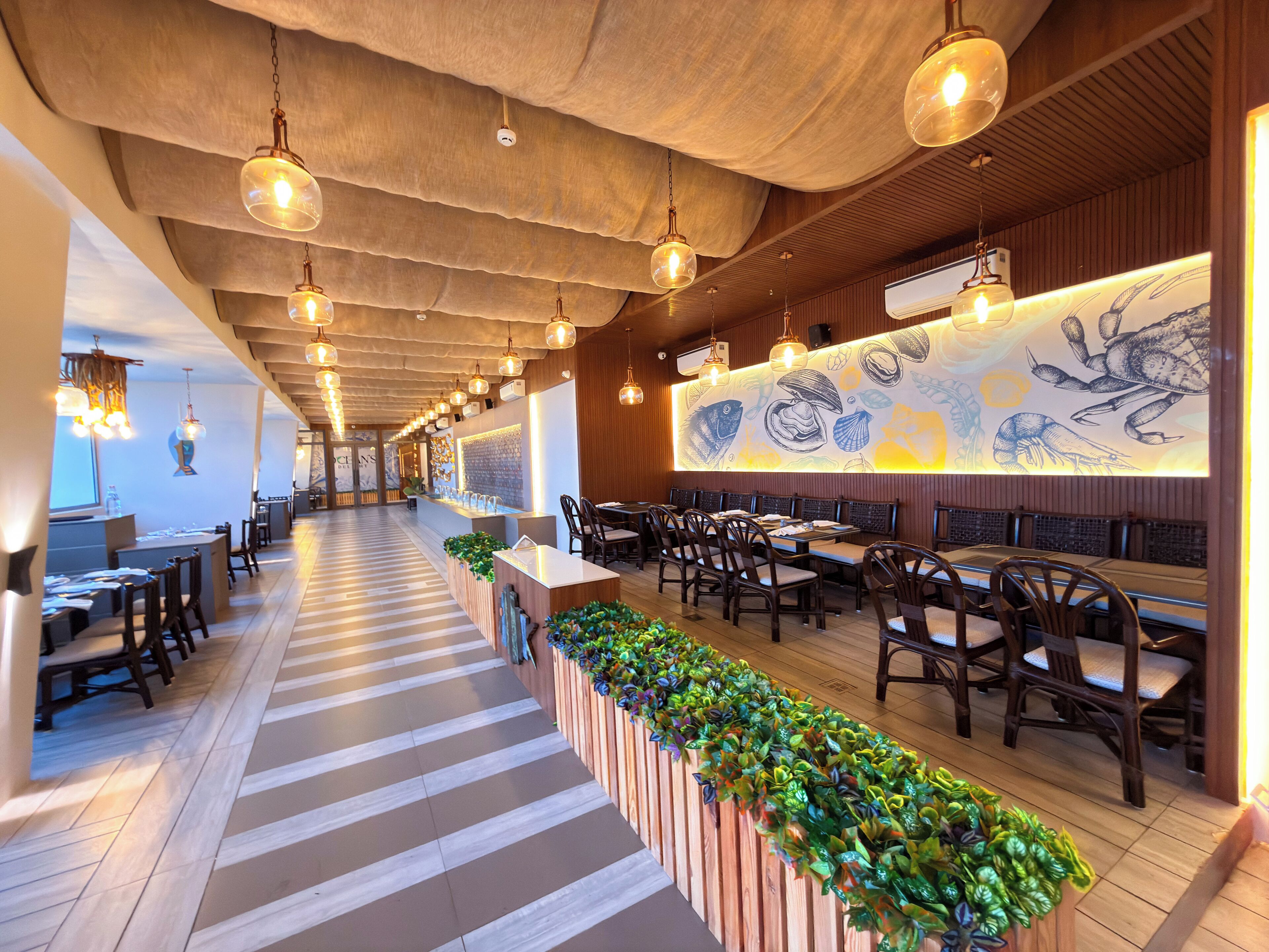 Ein Restaurant mit einer langen Theke, Holzsesseln und hängenden Pendelleuchten.