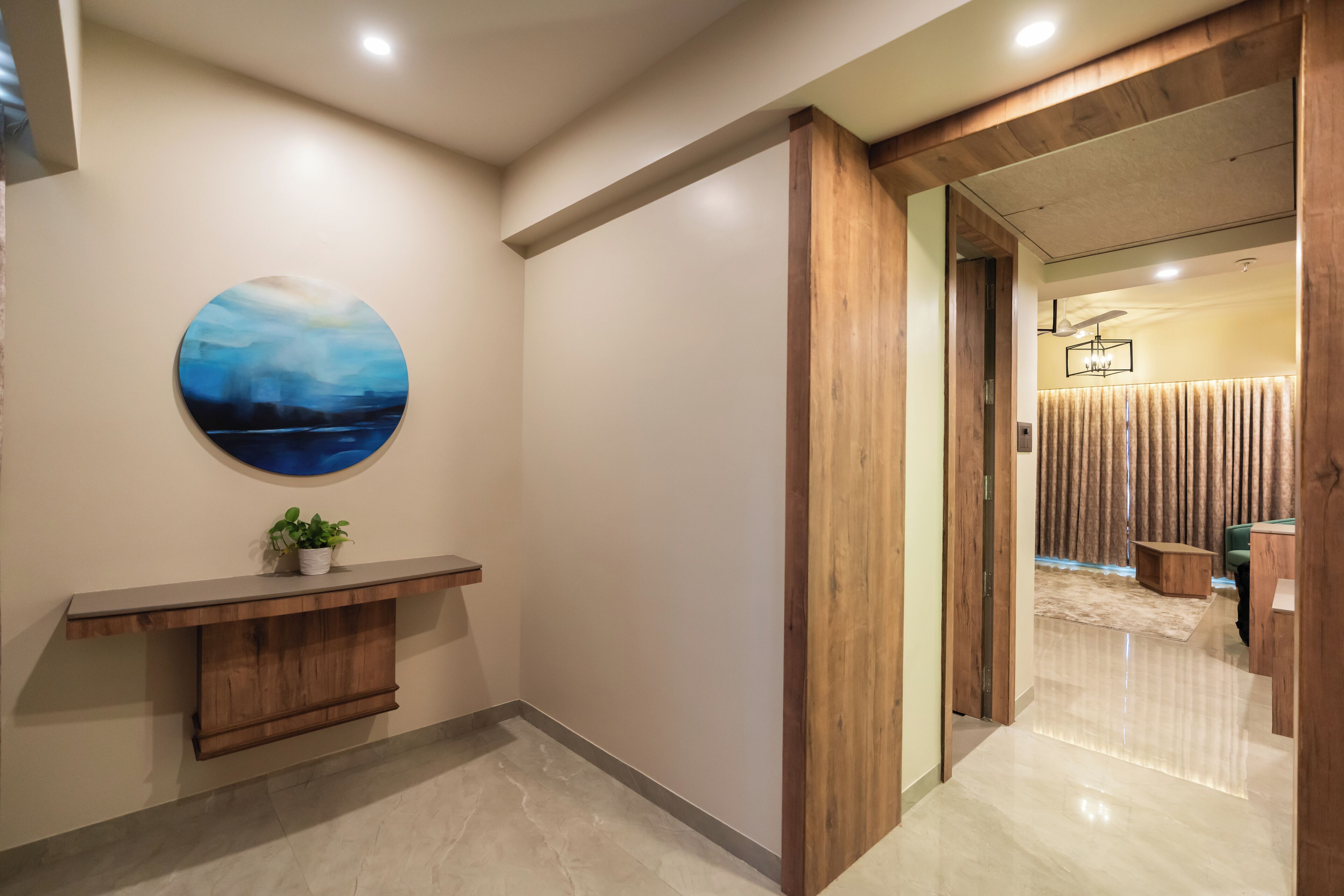 A hallway with a wooden bench, a round wall art, and a door leading to another room.