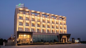 A modern hotel with a prominent sign, multiple balconies, and a large glass facade.