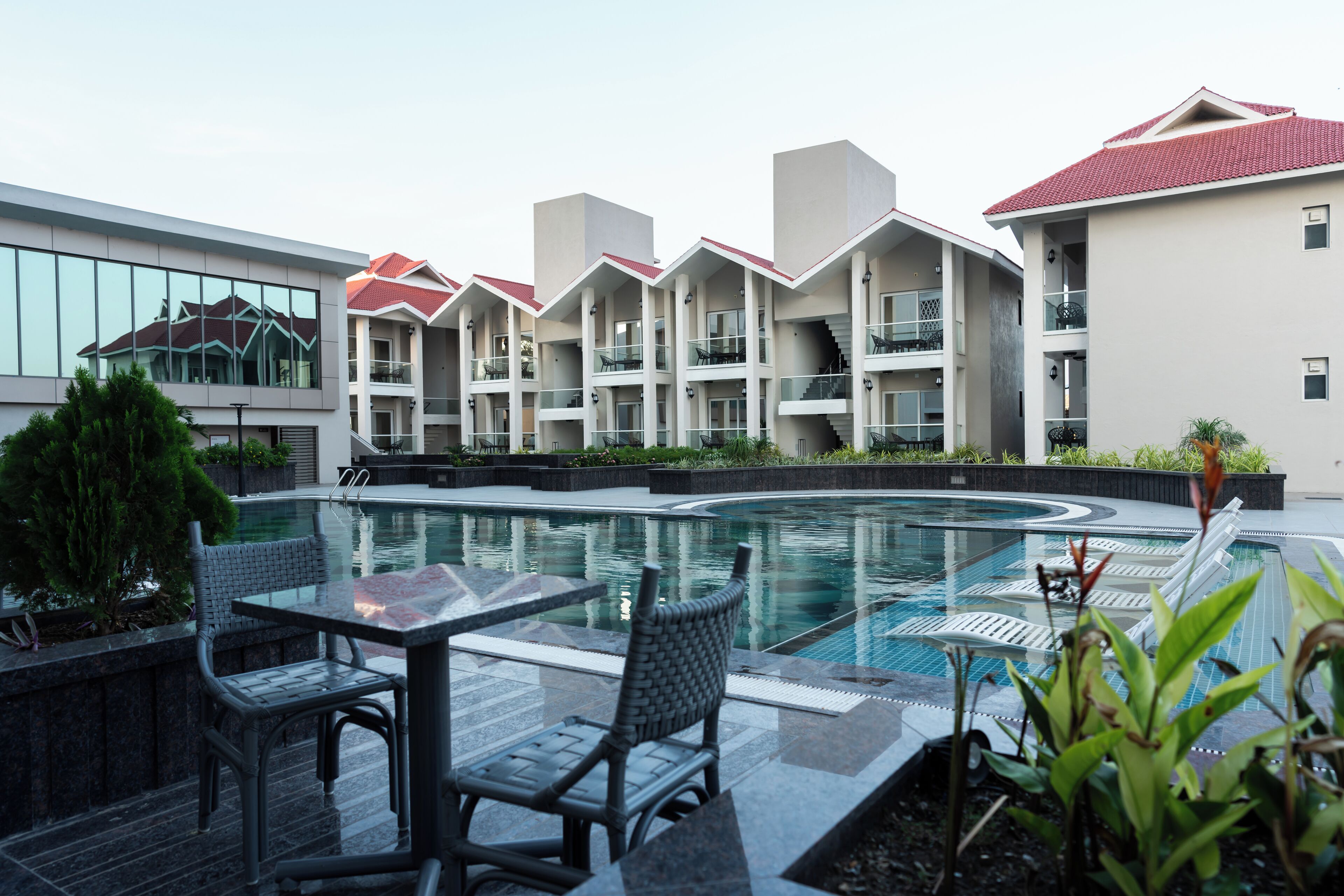 A modern hotel with a swimming pool, outdoor seating, and a landscaped garden.