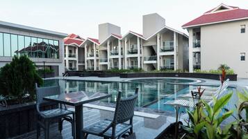 A modern hotel with a swimming pool, outdoor seating, and a landscaped garden.