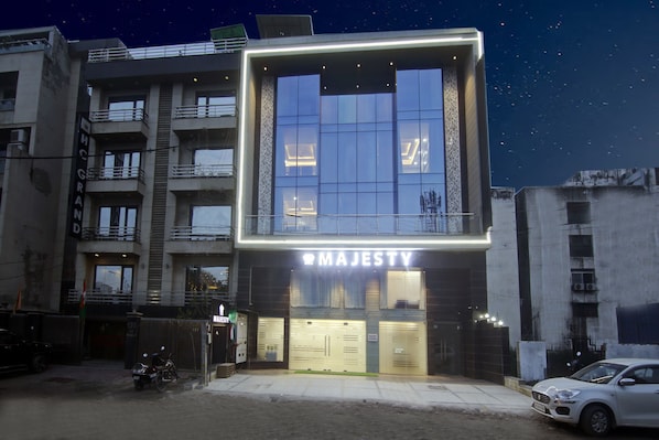 Een modern gebouw met een opvallend “MAJESTY”-bord, met een glazen gevel en een balkon op de bovenste verdieping.