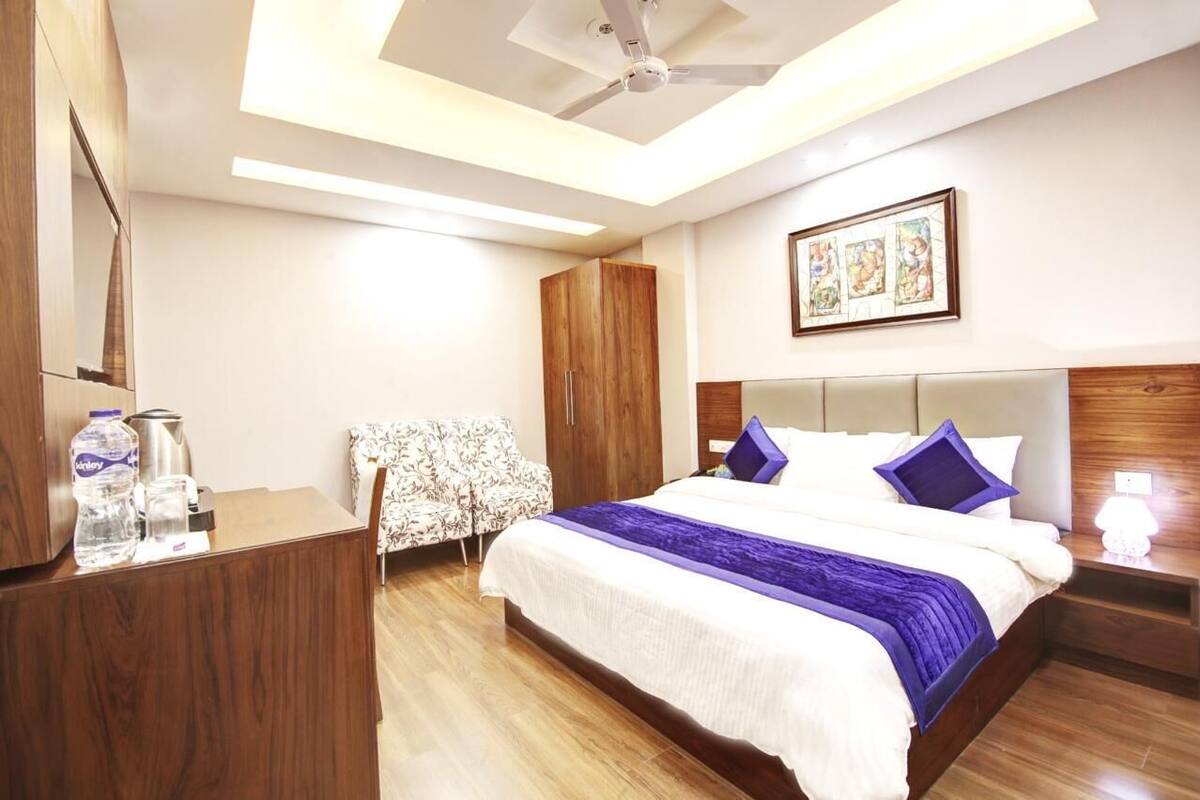 A hotel room with a bed, a desk, a wardrobe, and a ceiling fan.