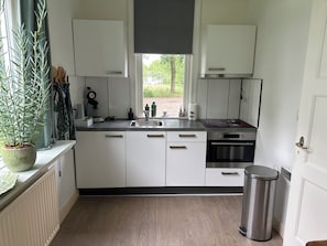 Una cocina moderna con gabinetes blancos, un lavamanos de acero inoxidable y un horno.