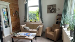 Ein Wohnzimmer mit Sofa, Sesseln, Couchtisch und Topfpflanzen.