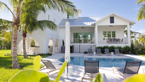 Una casa moderna con piscina, area relax esterna e palme.