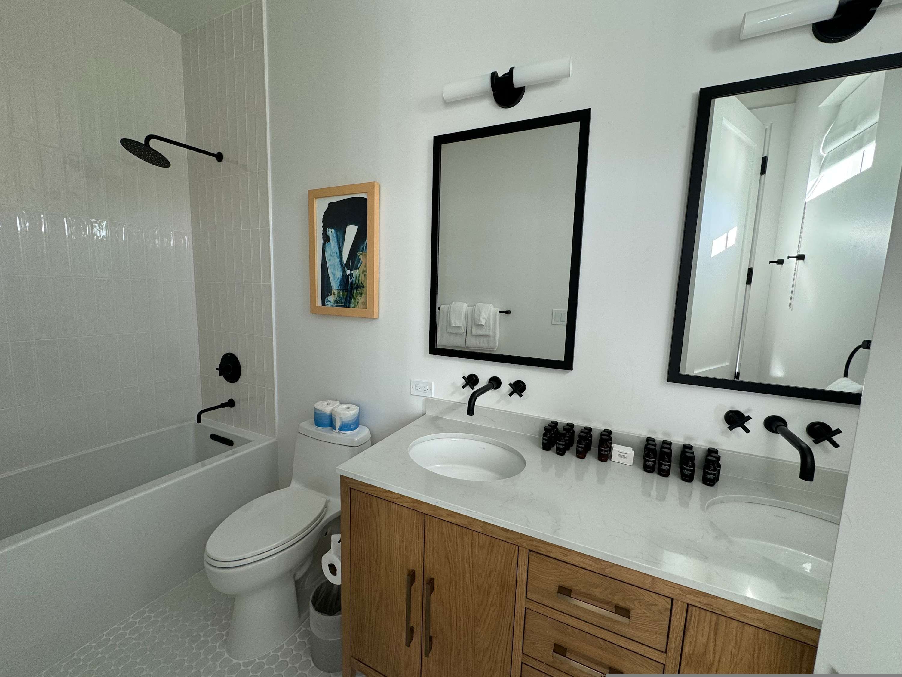 Ein modernes Badezimmer mit Badewanne, Toilette, Waschbecken und Spiegeln.