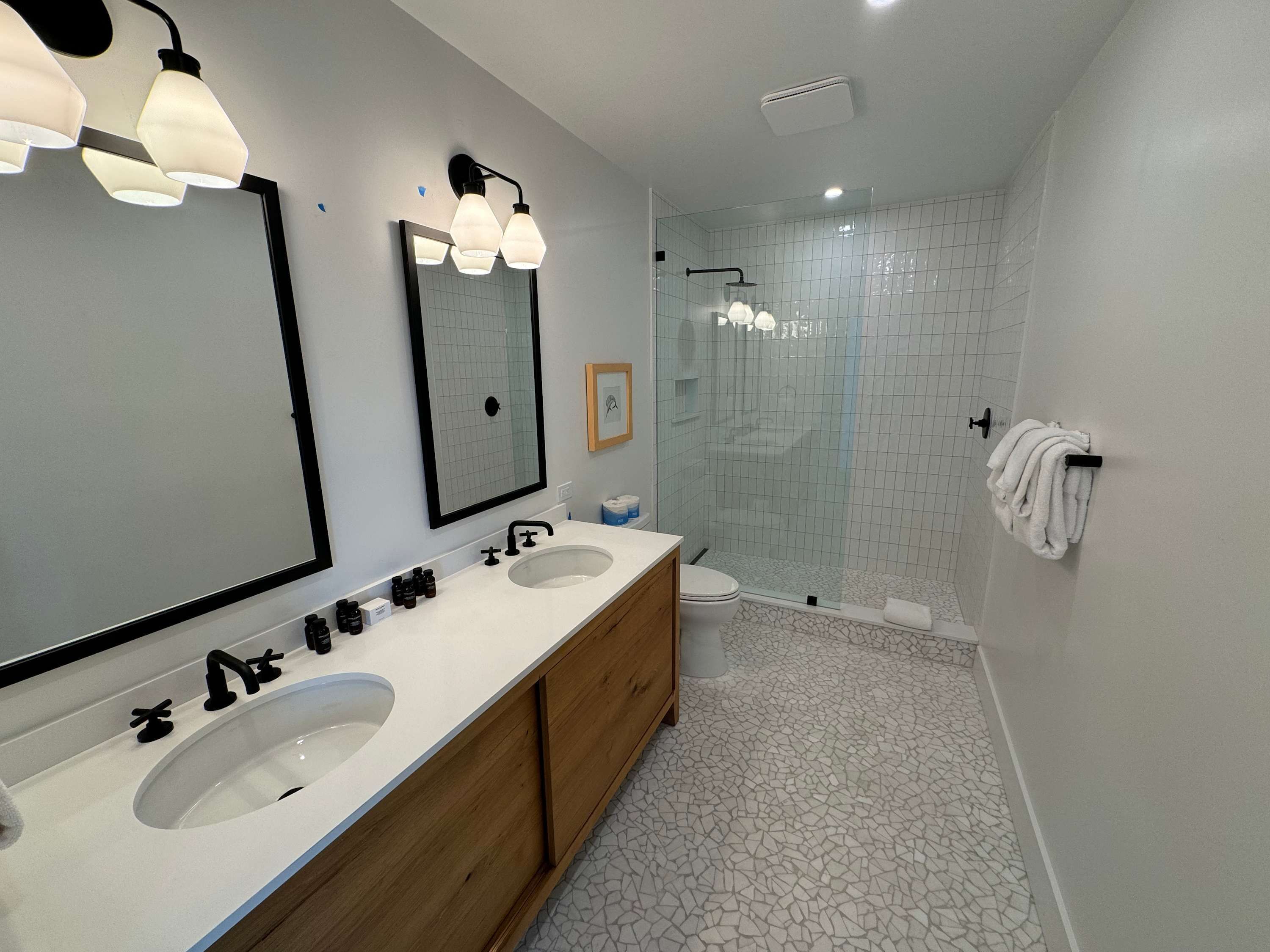 Un bany modern amb dues dutxes, un mirall gran i una cabina de vidre.