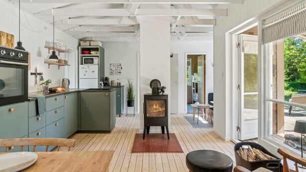 Una cocina moderna con una isla central, una zona de comedor con mesa de madera y una chimenea.