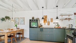 Una cocina moderna con una isla central, sillas de madera, una mesa de comedor y una estufa.