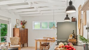 Cocina moderna con armarios de madera, una mesa de comedor y una isla grande con productos frescos.