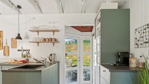 Una cocina con una isla de madera, una cafetera y vistas al exterior a través de un ventanal.