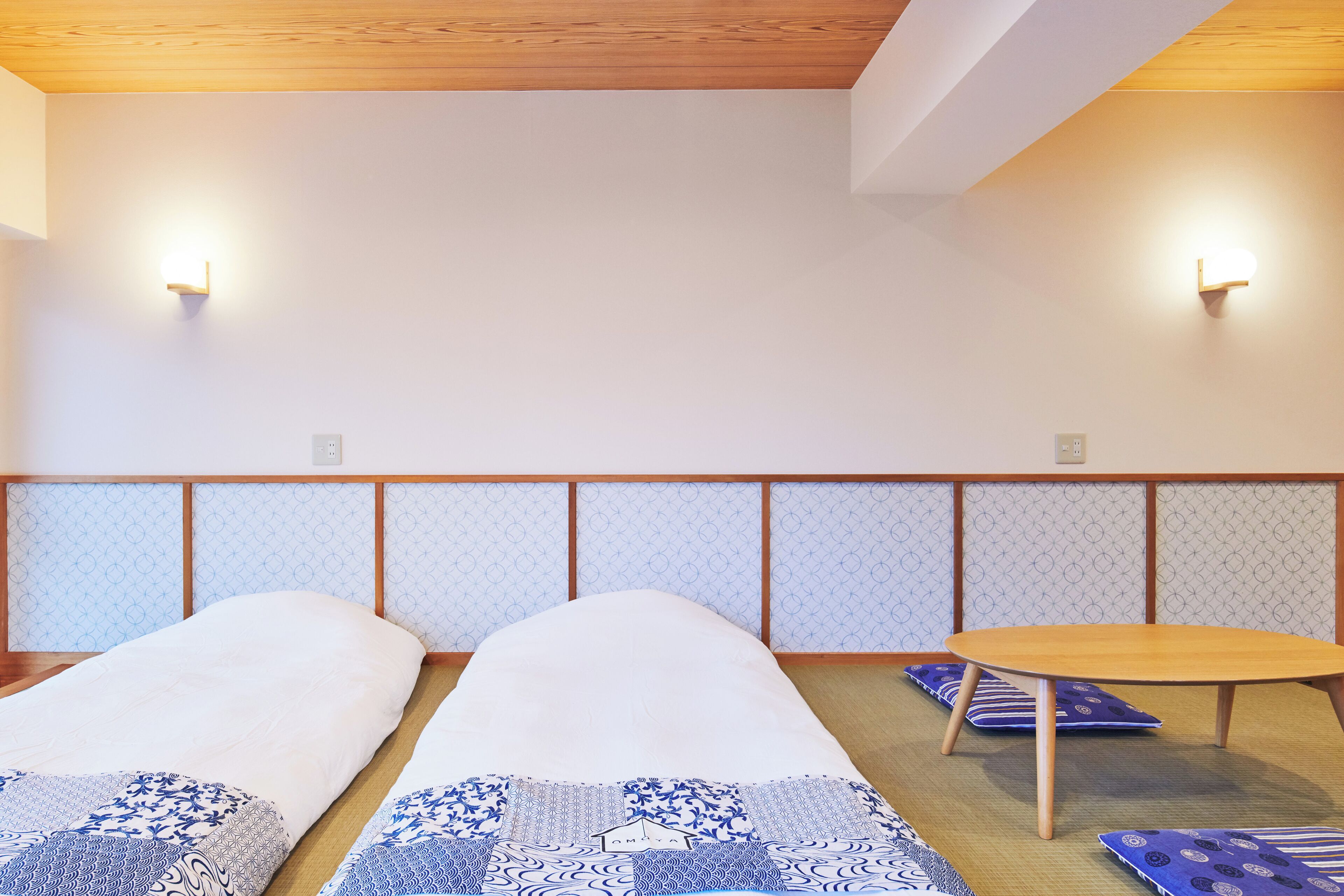 A room with two beds, a small round table, and a tatami mat floor.