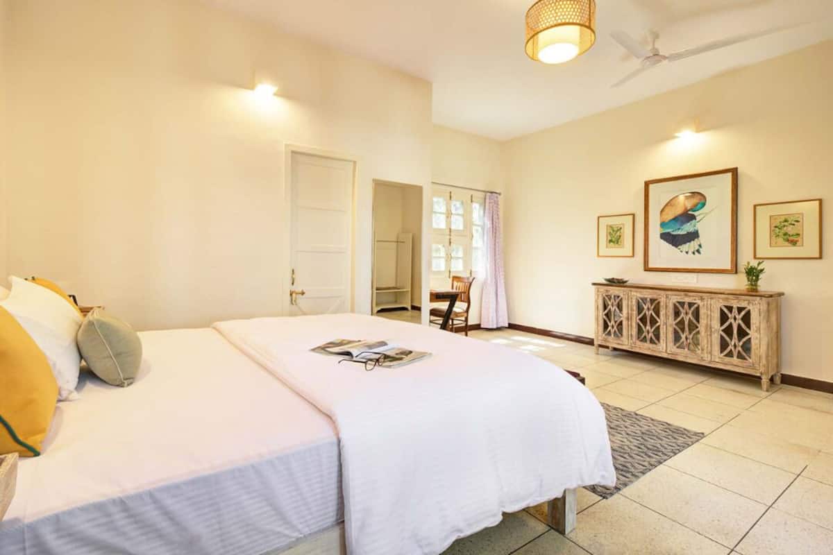 Una habitación de hotel con una cama, una mesita auxiliar, un armario y una puerta que da a otra habitación.