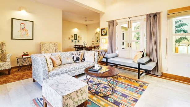A spacious living room with a sectional sofa, a coffee table, and a dining area in the background. - Avaanti Boutique Stay By Avaanti Stays (Udaipur)
