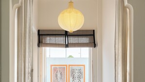 A cozy reading nook with a cushioned bench, a hanging light fixture, and framed artwork on the wall. - Avaanti Boutique Stay By Avaanti Stays (Udaipur)