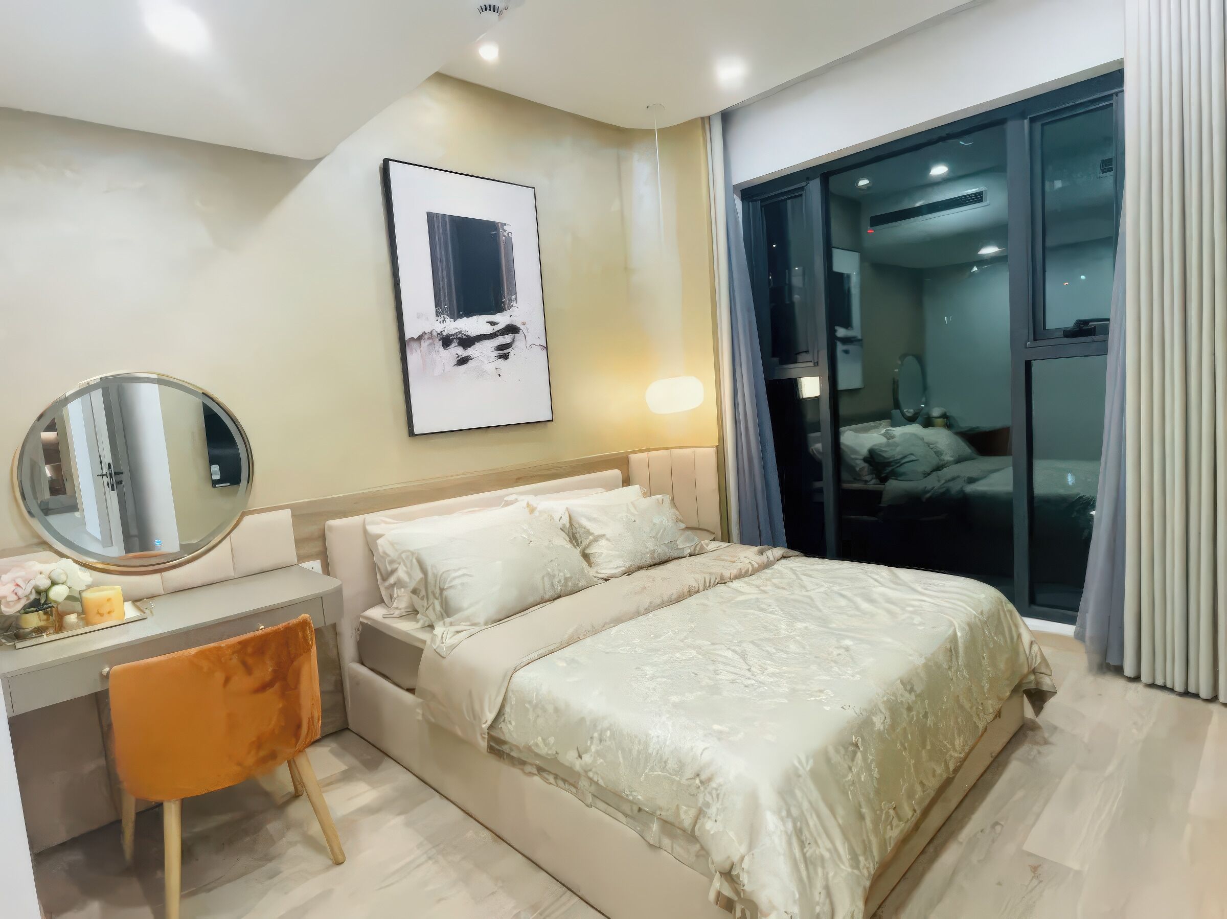 A modern hotel room with a bed, a desk, a chair, a round mirror, and a large window.