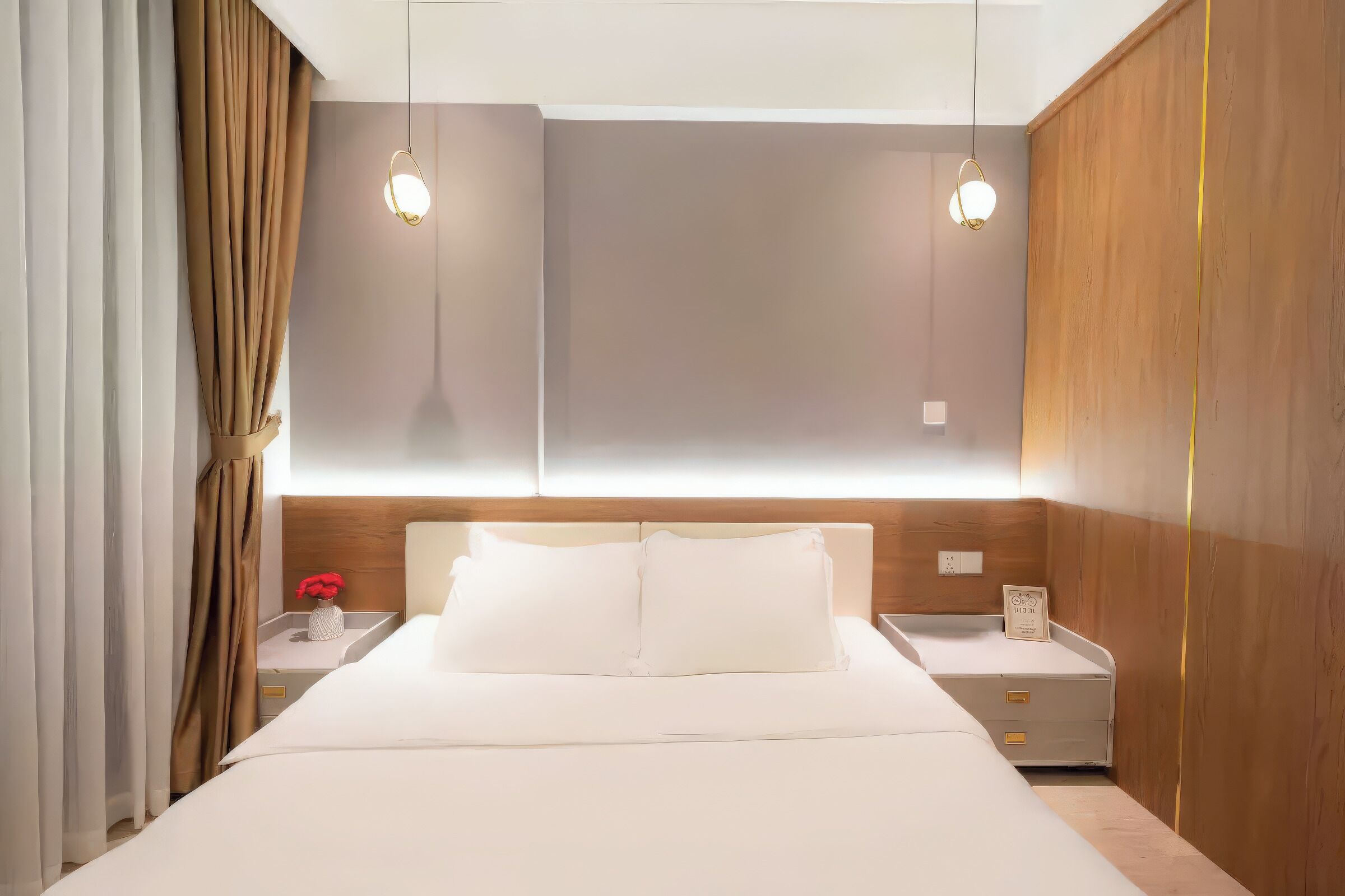 Ein modernes Hotelzimmer mit einem großen Bett, einem Holzkopfstück, Nachttischen und einem Beistelltisch mit Blumen.