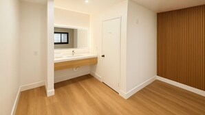 Un baño moderno con tocador blanco, espejo y suelo de madera.