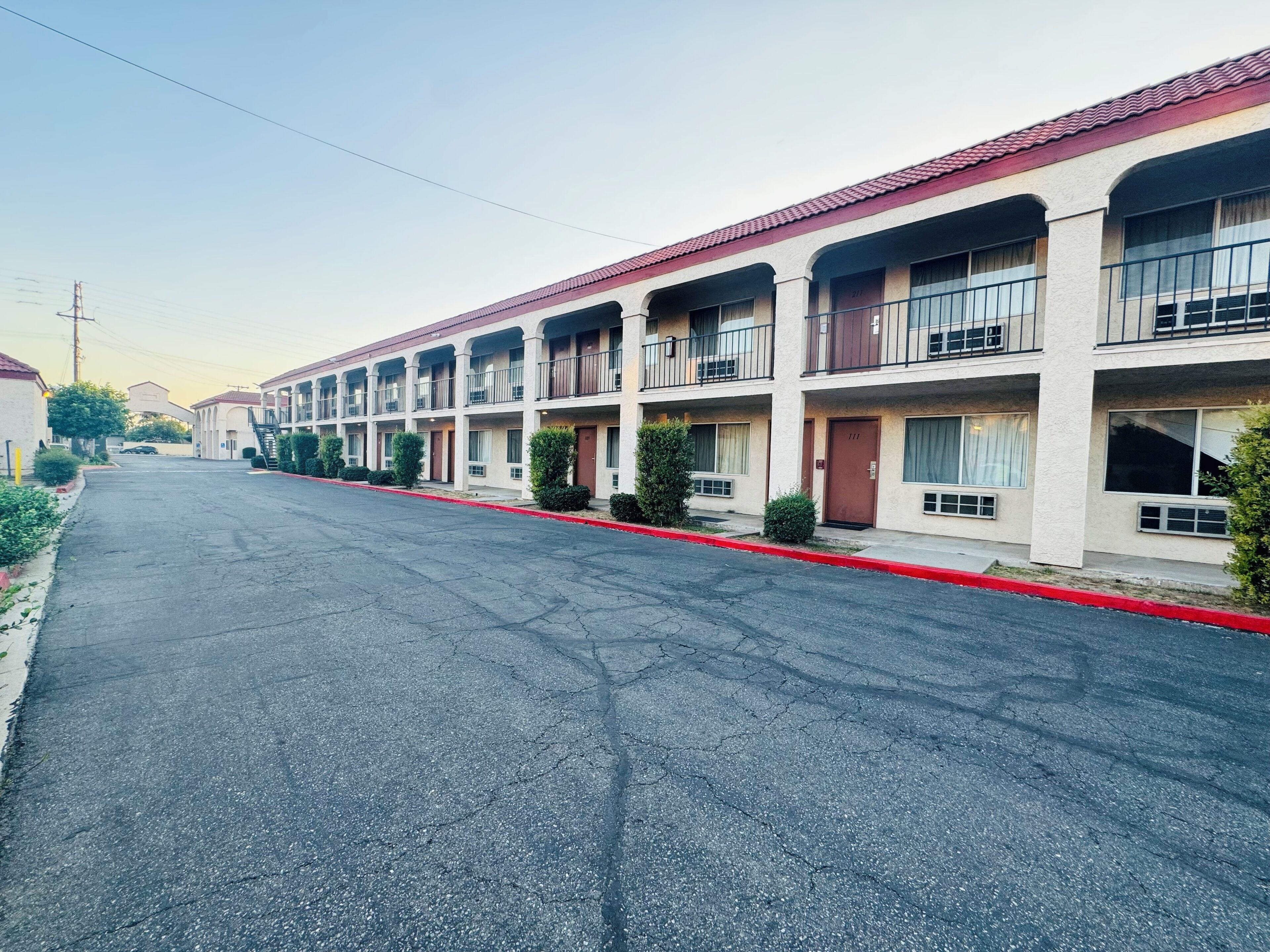 A row of motel buildings with multiple balconies, a red curb, and a clear sky.