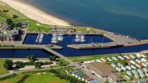 A marina with boats docked, a beach, and mobile homes. - Deluxe 2 bed en-suite, stunning views, parking (Nairn)