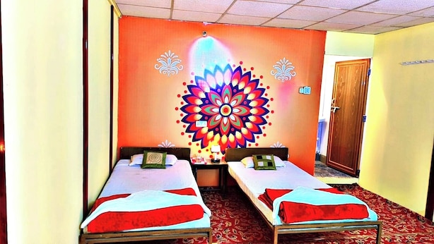A room with two single beds, a colorful wall mural, and a wooden door. - Divya Prayag Kumbh Camp  (Karchana)