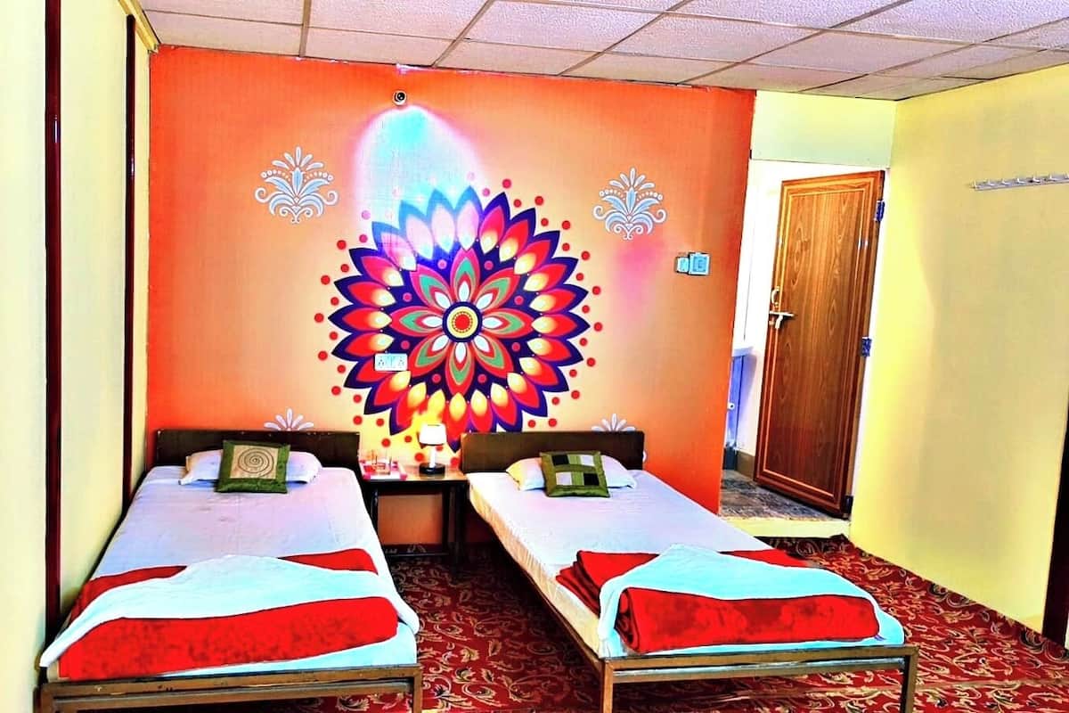A room with two single beds, a colorful wall mural, and a wooden door.