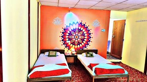 A room with two single beds, a colorful wall mural, and a wooden door. - Divya Prayag Kumbh Camp  (Karchana)