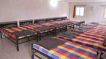 Una habitación con varias camas dispuestas en filas, cada una con una colcha de colores.