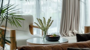 A modern living room with a white sofa, a round coffee table, a vase with dried plants, and a bowl of fruit. - Villa Amaluna (Canggu)