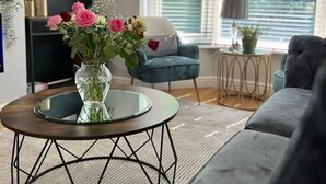 A modern living room with a round coffee table, a blue armchair, and a grey sofa. - Beautiful 4 Bed House in Sheffield (Sheffield)