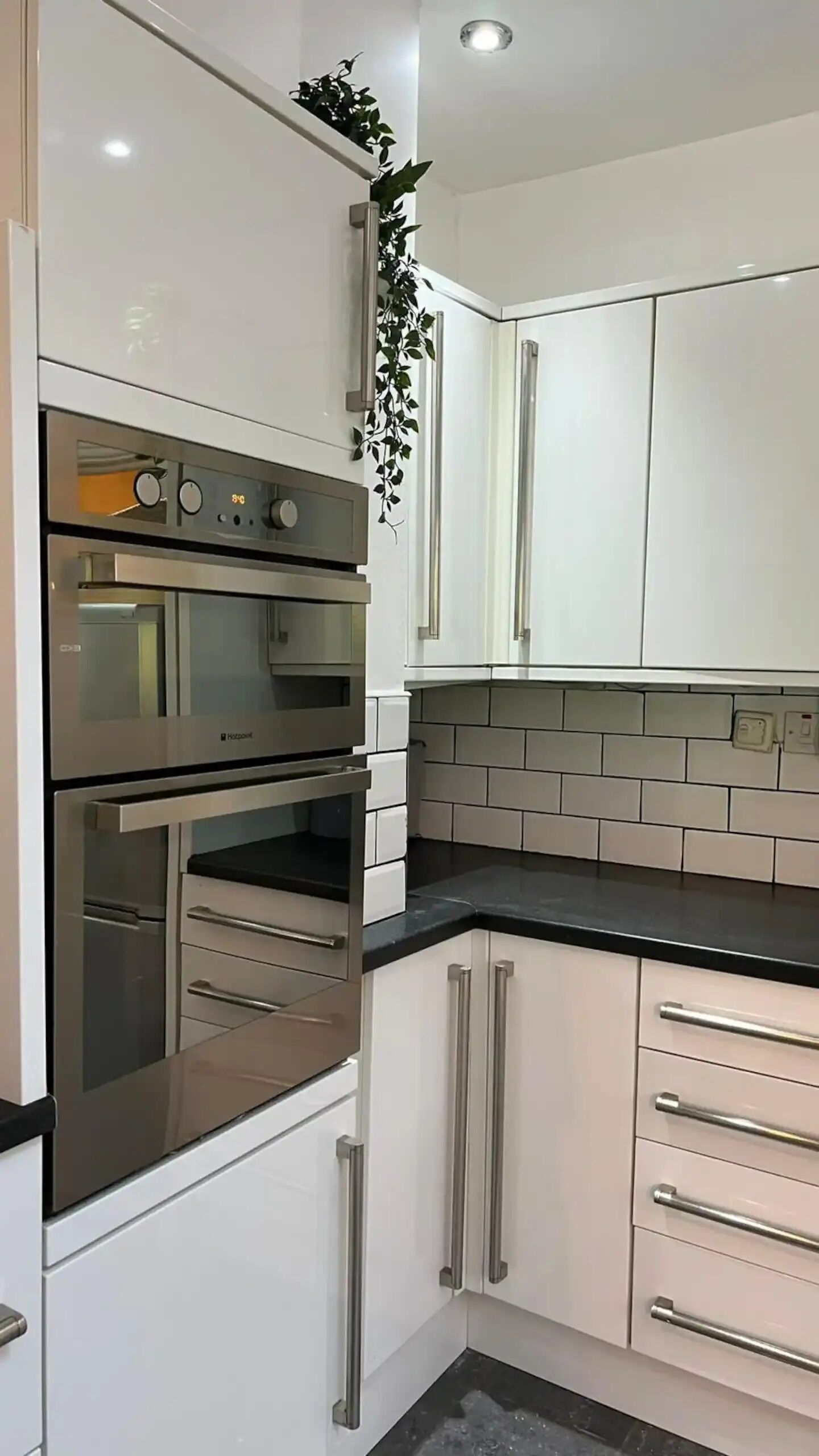 A modern kitchen with white cabinets, stainless steel appliances, and a black countertop.