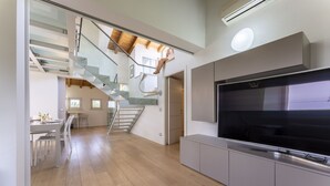 Un intérieur moderne comprenant un escalier, un coin repas et un grand téléviseur à écran plat.