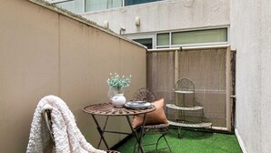 Eine kleine Terrasse im Freien mit einem runden Metalltisch, einem Stuhl und einem dekorativen Metallregal.