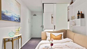 Ein ordentlich eingerichtetes Schlafzimmer mit einem Bett, einem Nachttisch und einem an der Wand befestigten Regal mit Dekoration.