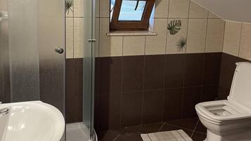 A bathroom with a shower, a toilet, and a sink.