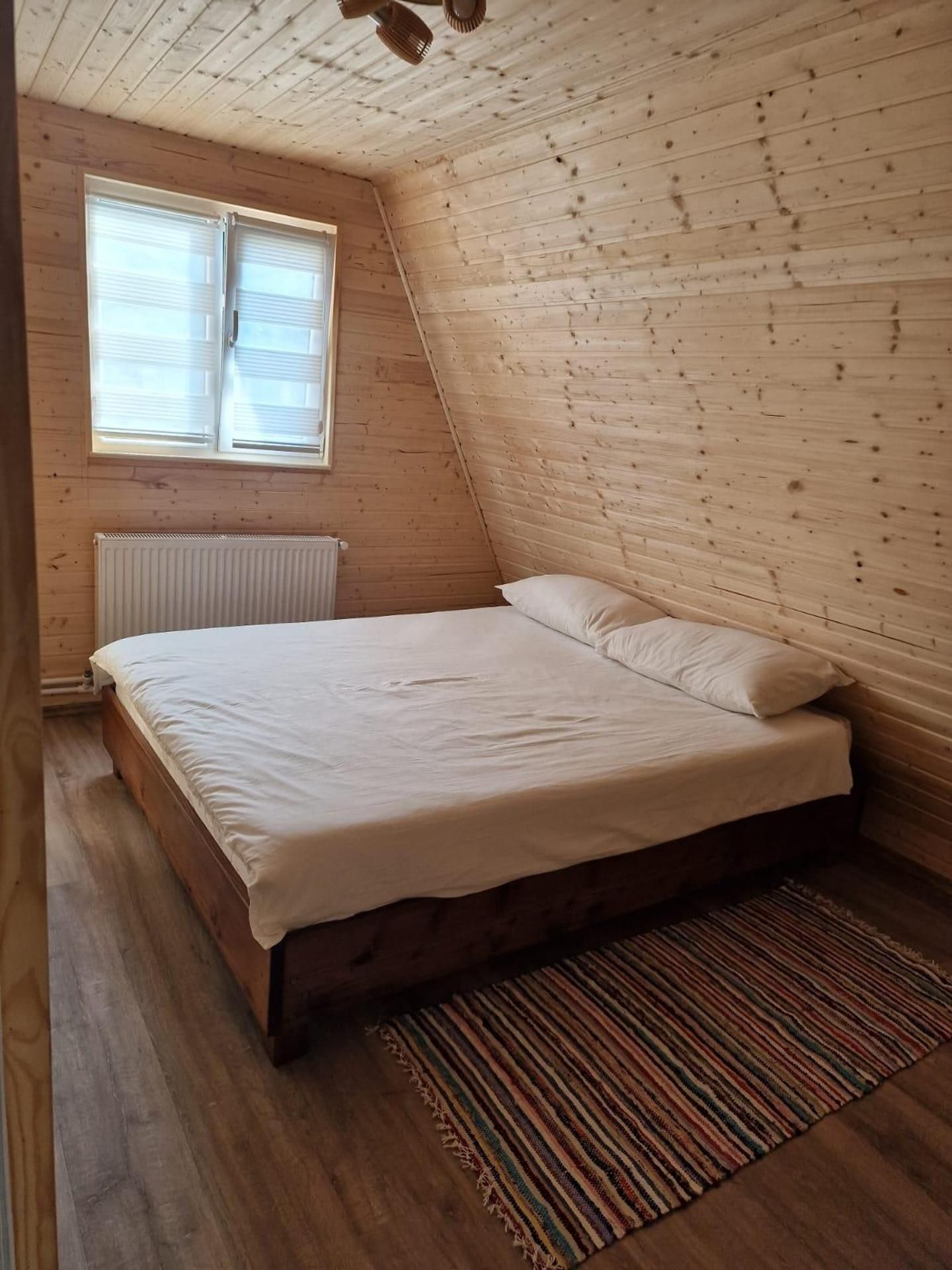 A single bed in a room with wooden walls and a sloped ceiling.